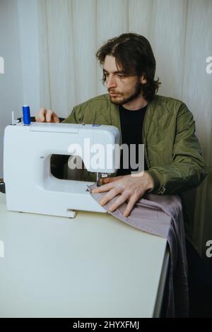 l'uomo sews su una macchina da scrivere in casa Foto Stock