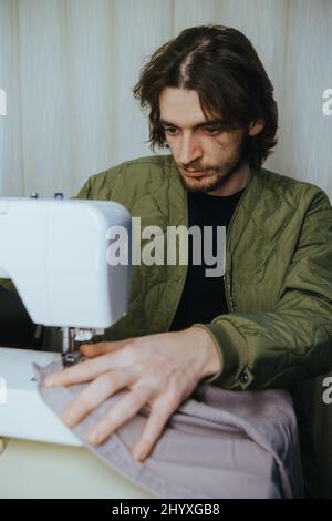 l'uomo sews su una macchina da scrivere in casa Foto Stock