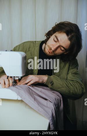 l'uomo sews su una macchina da scrivere in casa Foto Stock