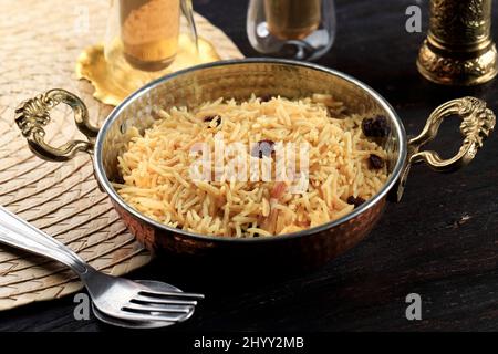 Kashmiri Pulao in riso basmati a grana lunga cotto con spezie e aromatizzato con zafferano e raisina, su sfondo di legno Foto Stock