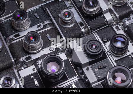 Le vecchie fotocamere retrò si trovano in file l'una rispetto all'altra con lenti svasate. Raccolta Foto Stock