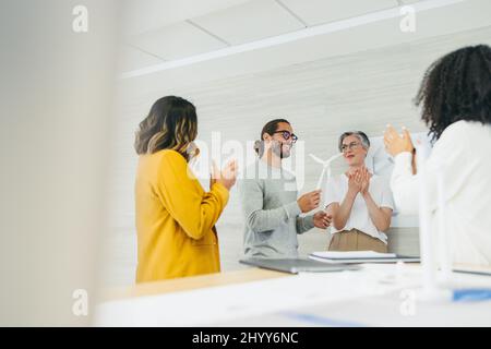 Designer di successo che applaudono il loro collega durante una riunione in un ufficio moderno. Gruppo di uomini d'affari innovativi che festeggia il loro compagno di squadra a Foto Stock