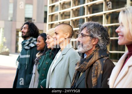 Diversi volti di gruppo di diverse età e razze con un aspetto aziendale. Ritratto all'aperto di persone d'affari Foto Stock