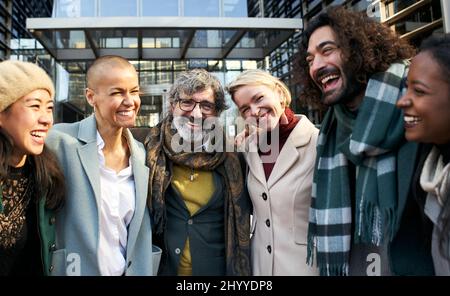 Lavoro di squadra di affari che parla e ride all'aperto. Persone felici e diverse che sorridono insieme. L'uomo e le donne insieme celebrano il successo nell'azienda di lavoro. Foto Stock