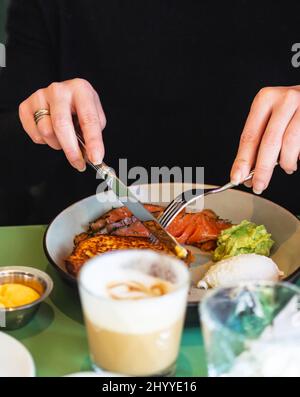 Primo piano su una giovane donna con le mani in mano come ella è avere la prima colazione Foto Stock