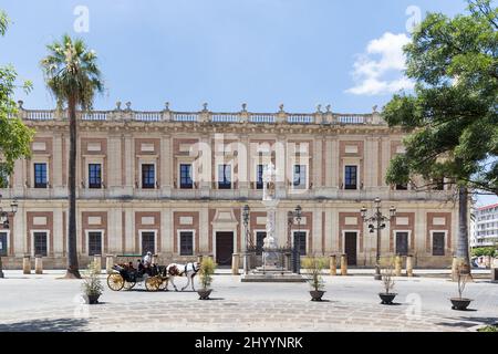 Edificio 'Archivo de Indias', situato nel centro di Siviglia in Piazza Triunfo. Tempio di Triunfo di fronte all'edificio. Carretto cavallo di passaggio Foto Stock