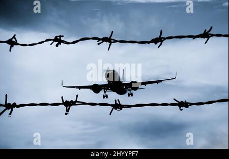 Aeroplano, aereo visto attraverso la recinzione di bordo del filo spinato. Immagine del concetto: Zona di volo NO, conflitto Ucraina Russia, recinzione di frontiera, attraversamento Foto Stock