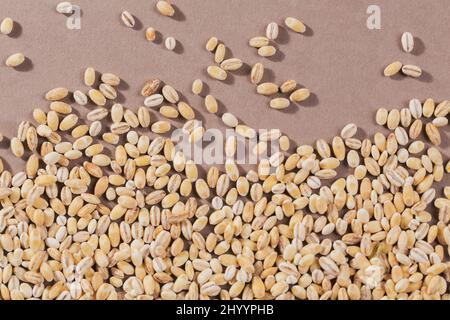 Vista dall'alto dell'orzo perlato crudo biologico. Grani di grano di orzo greggio essiccato rotto cereali come un astratto tessuto sfondo. Foto Stock
