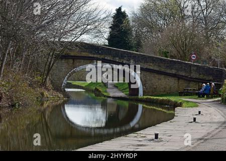 Persone sedute dal ponte canale, Leeds e Liverpool canale, Dowley Gap, Bingley Foto Stock