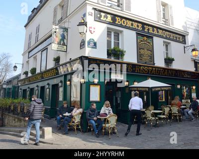 Parigi, Francia - 5 marzo 2022: Persone alla terrazza all'aperto o ristorante storico nel pittoresco quartiere di Montmartre a Parigi, Francia. Foto Stock