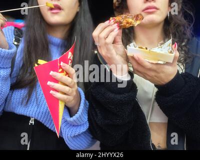 Vista ravvicinata di due donne che mangiano fast food all'aperto Foto Stock