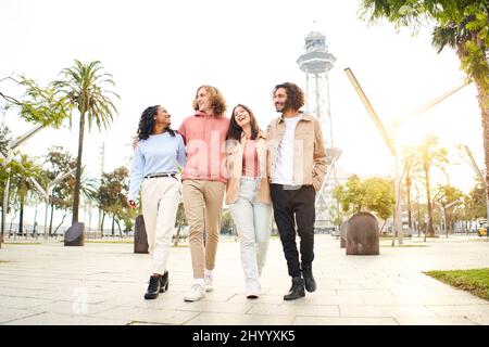 Un felice gruppo di amici cammina nel parco della città turistica. Persone che godono di tempo libero insieme. Foto Stock