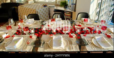 Tavolo da pranzo decorato con petali di rosa e candele votive Iittala in attesa di cena ospiti. Foto Stock