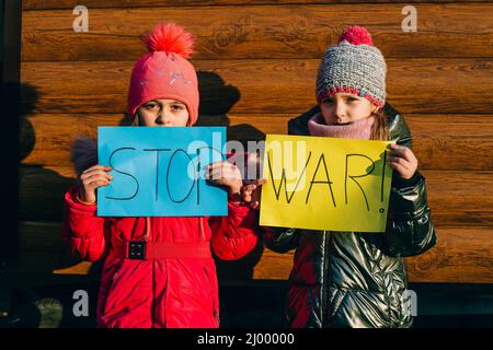 Giovani patrioti, attivisti per bambini. Piccole ragazze ucraine che chiedono di fermare la guerra sollevare banner con iscrizione fermare la guerra in Ucraina Foto Stock