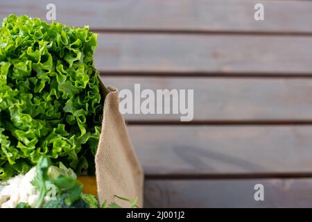 Verdure in un sacchetto con sfondo di legno Foto Stock