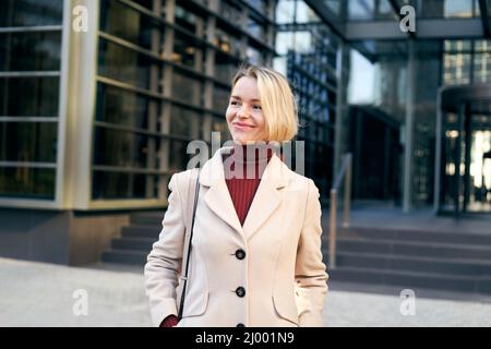 Una donna d'affari sorridente di mezza età fuori da un edificio di uffici. Gente corporativa allegra. Foto Stock