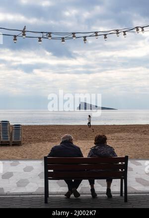 Coppia di turisti seduti sul lungomare di Benidorm tra le palme Foto Stock