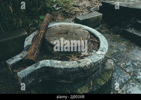 Primo piano di una macina con un log di legno in cima all'esterno in una giornata piovosa Foto Stock