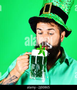 Giorno delle Patricks. Uomo portato in cappello leprechaun bere birra verde. Marzo 17. Chiodi di garofano nella birra. Primo piano. Foto Stock