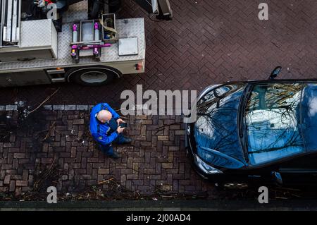 Amsterdam, Paesi Bassi 25 febbraio 2022: Un funzionario di parcheggio che scrive una multa sul suo telefono prima di trainare l'auto ad Amsterdam, Paesi Bassi Foto Stock