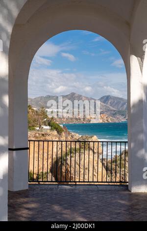 Bellissimo paesaggio visto attraverso un arco sul balcone d'Europa, Nerja città, Malaga. Vista sulla spiaggia di la Chalaonda con le montagne della Sierra Nevada sul retro Foto Stock