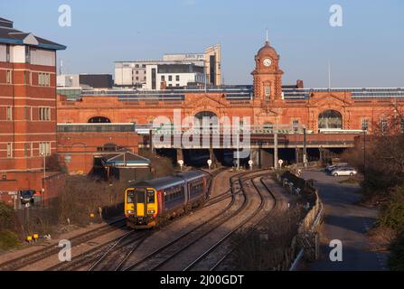 East Midlands treni classe 156 treno 156414 lasciando la stazione ferroviaria di Nottingham con l'edificio della grande stazione alle spalle. Foto Stock