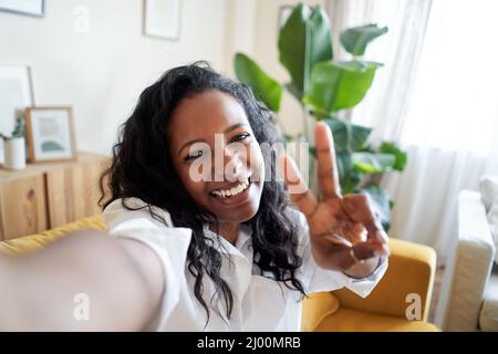 Giovane donna attraente utilizzando la fotocamera di smartphone prendendo divertente selfie a casa Foto Stock