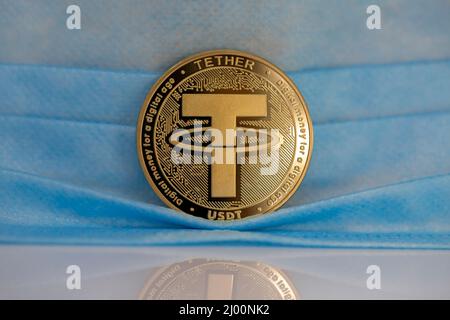 MODULO di RACCORDO USDT criptovaluta moneta fisica posto accanto alla maschera facciale. Foto Stock