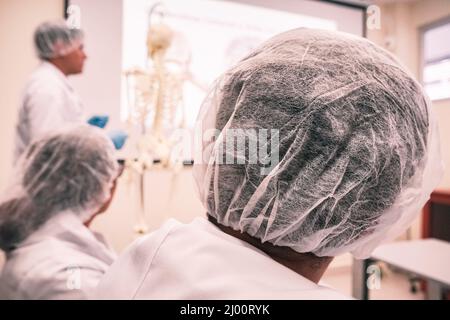 Studenti di medicina irriconoscibili e professore vestito da medico durante una sessione di studio Foto Stock