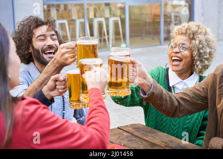 Gruppo di amici che si divertono durante una festa. Gente felice ridendo e tostando la birra. Foto Stock