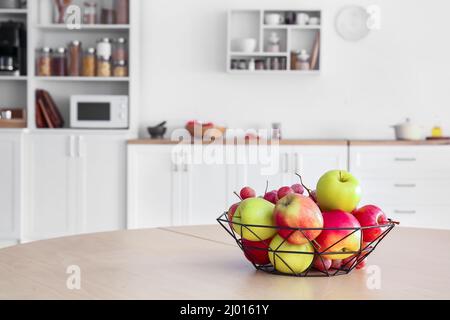 Cestino con mele e uva sul tavolo da pranzo in cucina Foto Stock