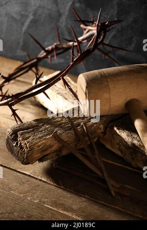 Corona di spine con croce di legno, mazzuolo e unghie su tavola Foto Stock