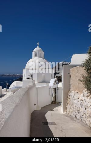 Un tipico vicolo che conduce ad una cappella ortodossa imbiancata sull'isola di Santorini in Grecia Foto Stock