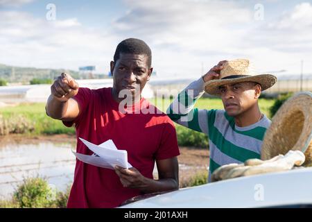 Due agricoltori con documenti che parlano in azienda Foto Stock