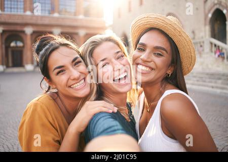 Tre giovani donne di hipster sorridenti in abiti estivi. Ragazze che scattano foto autoritratto selfie su smartphone.Models posing in the Street.Female mostrando Foto Stock