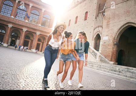 Tre amici di razza mista che si divertono in città durante le vacanze estive. Le donne ridono all'aperto Foto Stock