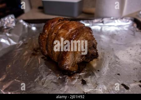 Primo piano, focalizzazione selettiva su un succoso arrosto di chashu di maiale poggiato su foglio di stagno dopo essere stato cotto Foto Stock