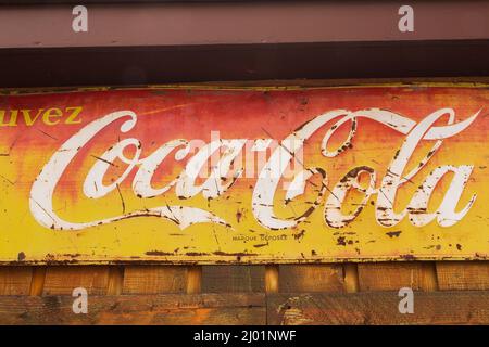 Vintage Coca Cola soft drink azienda rettangolare metallo pubblicità segno per i consumatori di lingua francese esposto su rustico legno tavola parete. Foto Stock