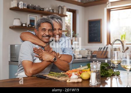 La nostra casa è piena di amore. Ritratto di una coppia matura felice che cucinano un pasto insieme a casa. Foto Stock