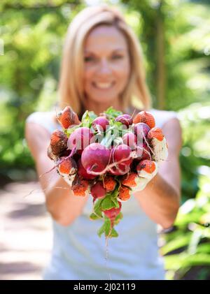 La salute del cuore è nelle sue mani. Una donna che tiene fuori le verdure appena raccolte. Foto Stock