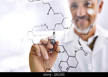 La chimica lo rende felice. Shot di uno scienziato maschile maturo che lavora con formule chimiche nel suo laboratorio. Foto Stock