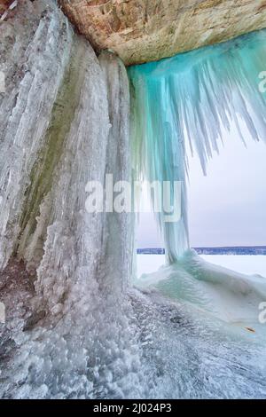 Ghiaccioli blu d'inverno pendenti da rocce vicino al lago Foto Stock