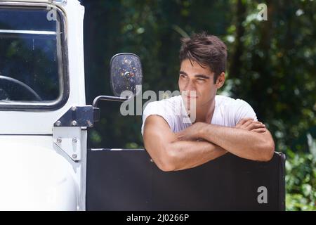 Un'ultima occhiata alla foresta prima di tornare a casa. Un bel giovane uomo appoggiato sulla porta dell'auto mentre si trova fuori nella foresta. Foto Stock