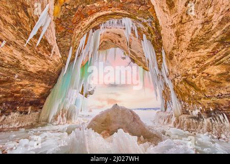 Grande ingresso nella grotta di ghiaccio coperto di ghiaccioli blu e verdi e di ghiaccio rotto Foto Stock