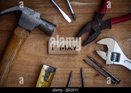 Testo su blocco di legno - 1st maggio con fondo strumenti di lavoro. Concetto del giorno del lavoro. Foto Stock