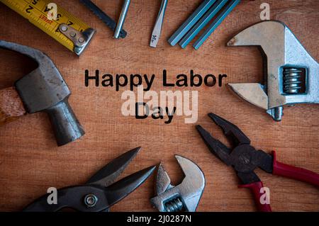 Testo su scrivania in legno - Happy Labor Day con strumenti di lavoro sfondo. Concetto del giorno del lavoro. Foto Stock