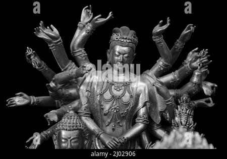 Statua Shiva multi armato isolata su sfondo nero con percorso di taglio. Statua del Buddha con molte braccia in un tempio buddista Foto Stock