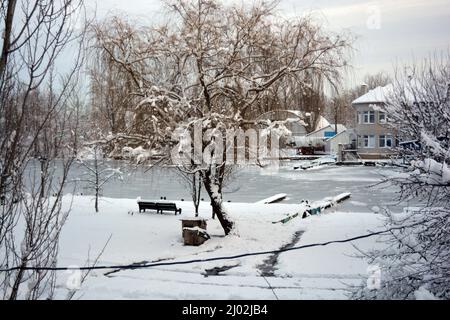 Un bellissimo e insolito paesaggio invernale, una piccola stazione di barche Ucraina sul fiume Dnipro, garage, barche, imponenti alberi ricoperti di neve bianca. Foto Stock