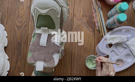 Sneaker da donna con disegno a spazzola su tavolo in legno. Foto Stock