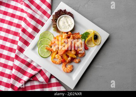 Gamberetti piccanti all'aglio in piatto bianco su sfondo grigio Foto Stock